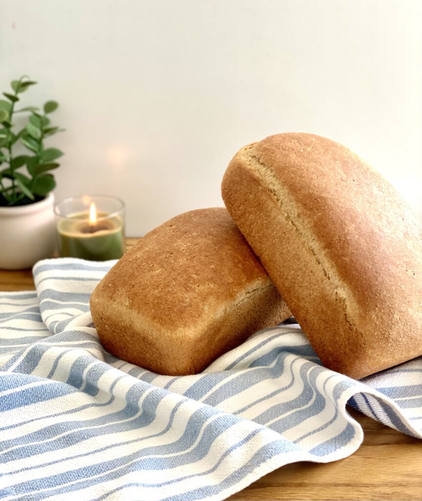 Rustic homemade bread made with freshly milled flour, featuring a golden crust and soft, airy crumb on a wooden cutting board.