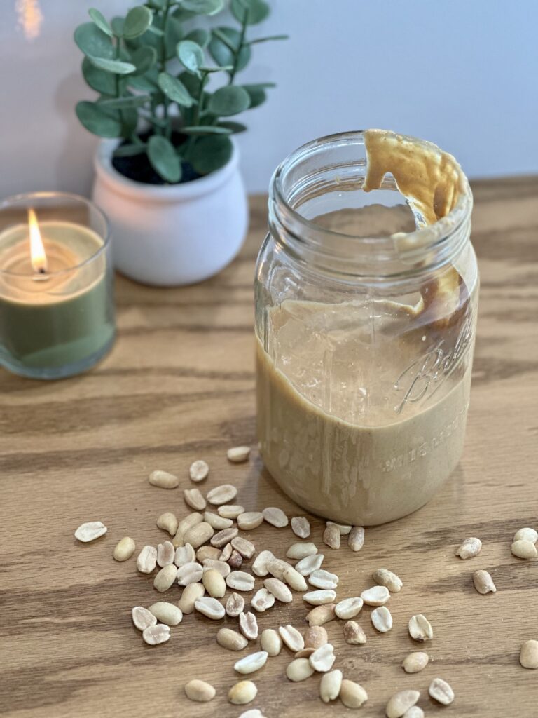 Homemade peanut butter in a glass jar with a spoon, made from roasted peanuts