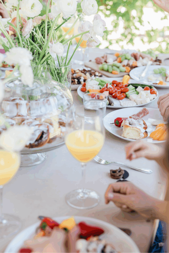 A beautifully arranged brunch table with fresh flowers, colorful plates of food, and mimosas, creating a cozy and inviting atmosphere.