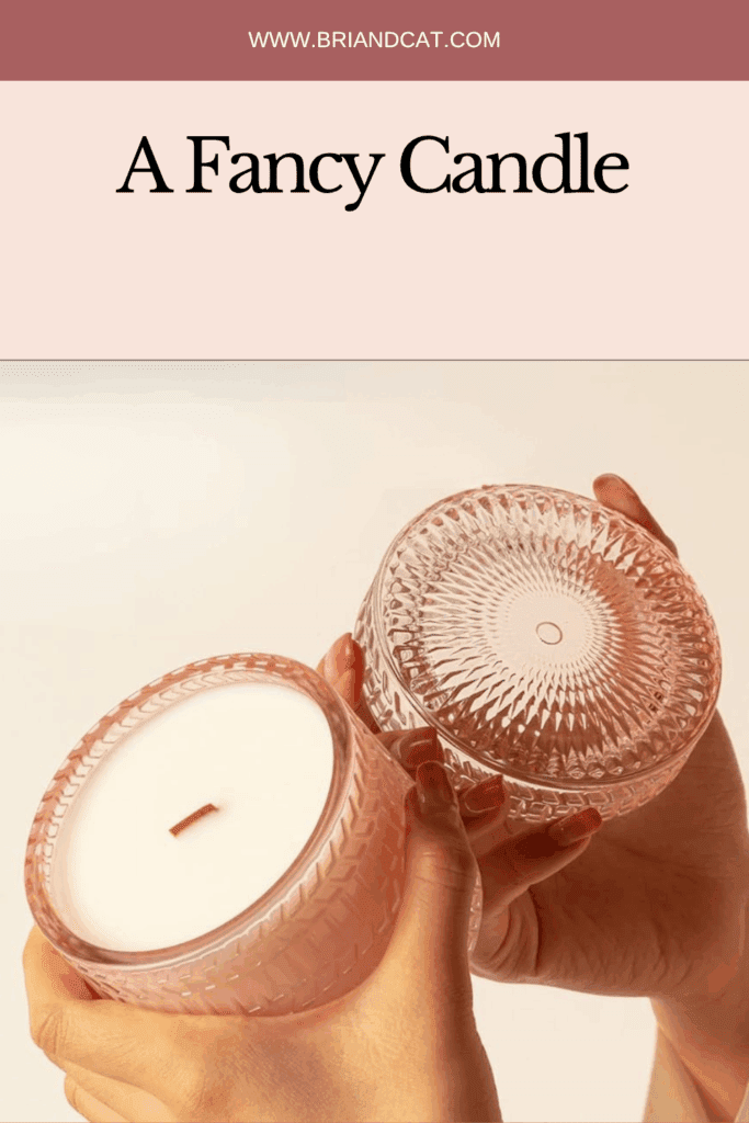 A close-up of two hands holding a pink glass candle with a decorative lid, showcasing the elaborate design of the candle holder.