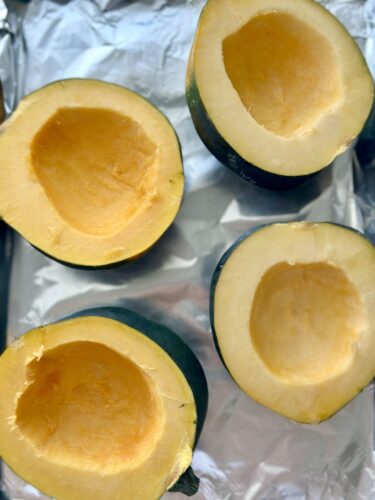 Halved acorn squashes resting on aluminum foil, ready for roasting.