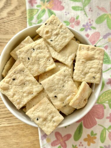 A bowl filled with homemade everything bagel crackers, showcasing their crisp texture and seasoning.
