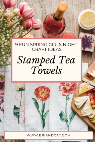 A decorative flat lay of stamped tea towels featuring colorful floral designs, accompanied by a bottle of rosé wine, fresh strawberries, lemons, and a cheese platter, creating a cheerful and inviting spring atmosphere.