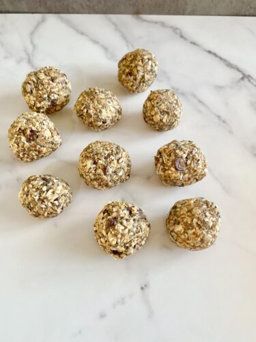 A group of homemade energy balls made from oats and nuts, arranged on a marble surface.
