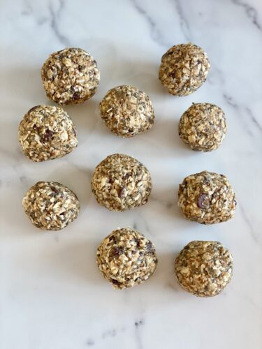 A group of healthy energy balls made from oats and nuts arranged on a marble surface.