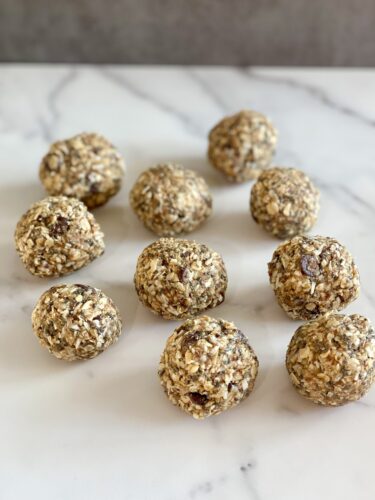 A group of oatmeal energy balls arranged on a marble countertop.