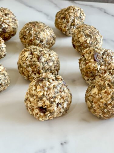 A close-up view of several round, healthy snack balls made from oats and nuts, arranged neatly on a marble surface.