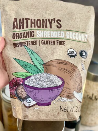 A bag of Anthony's Organic Shredded Coconut, labeled unsweetened and gluten-free, featuring a bowl of shredded coconut and a coconut shell illustration.