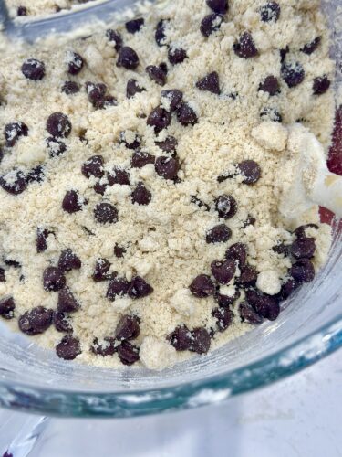 Bowl of chocolate chip cookie dough mixture with chocolate chips and a crumbly texture.