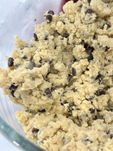 Close-up of chocolate chip cookie dough in a glass bowl.