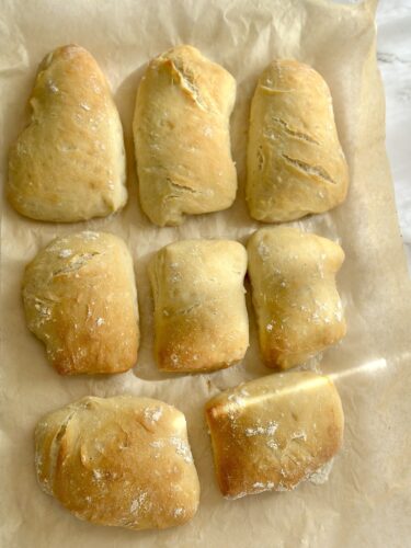 Freshly baked bread rolls arranged on parchment paper.