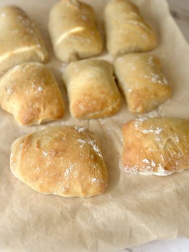 Freshly baked bread rolls arranged on parchment paper.