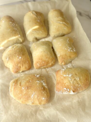 Freshly baked bread rolls arranged on parchment paper