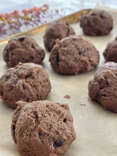 Freshly shaped chocolate cookie dough balls on a baking tray lined with parchment paper.
