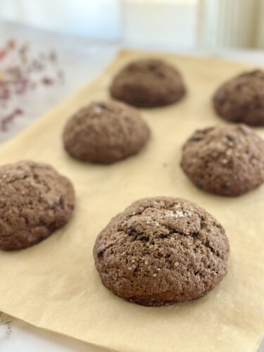Freshly baked chocolate cookies placed on parchment paper.