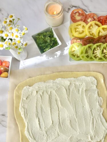 Whipped feta spread evenly over puff pastry with a one inch border left around the edges