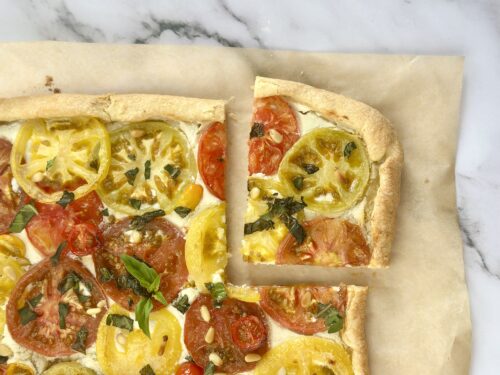 Heirloom tomato puff pastry tart sliced into squares and served as an appetizer
