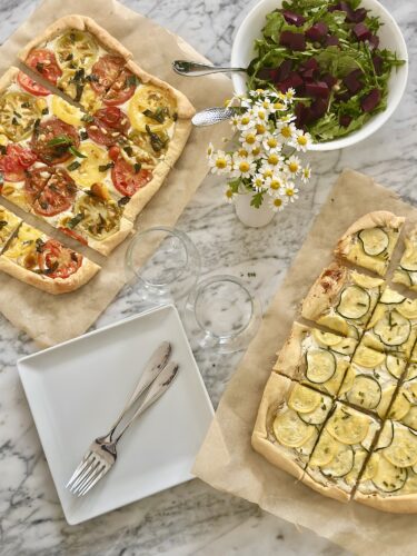 Finished tomato puff pastry tart garnished with fresh basil leaves and pine nuts